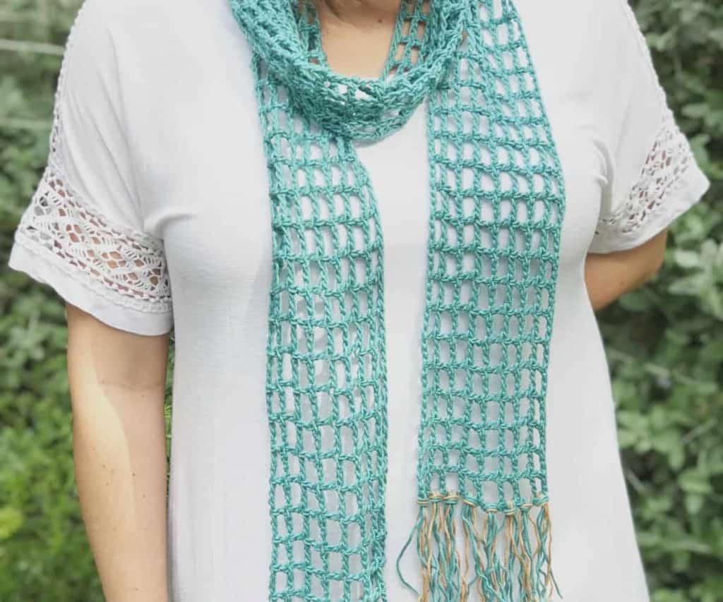 Teal mesh crochet skinny scarf on woman in white shirt.