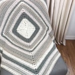 Center out square blanket in white and grey draped on chair.