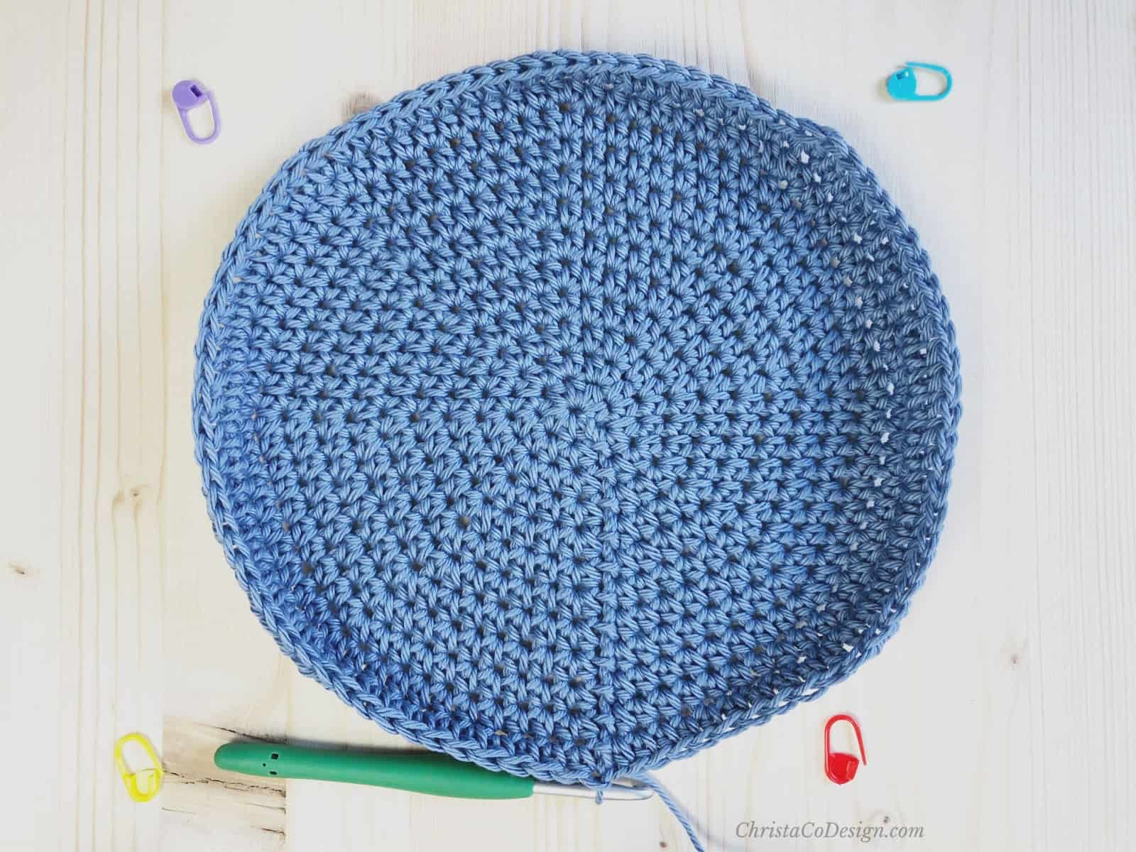 Blue round crochet circle with stitch markers removed.