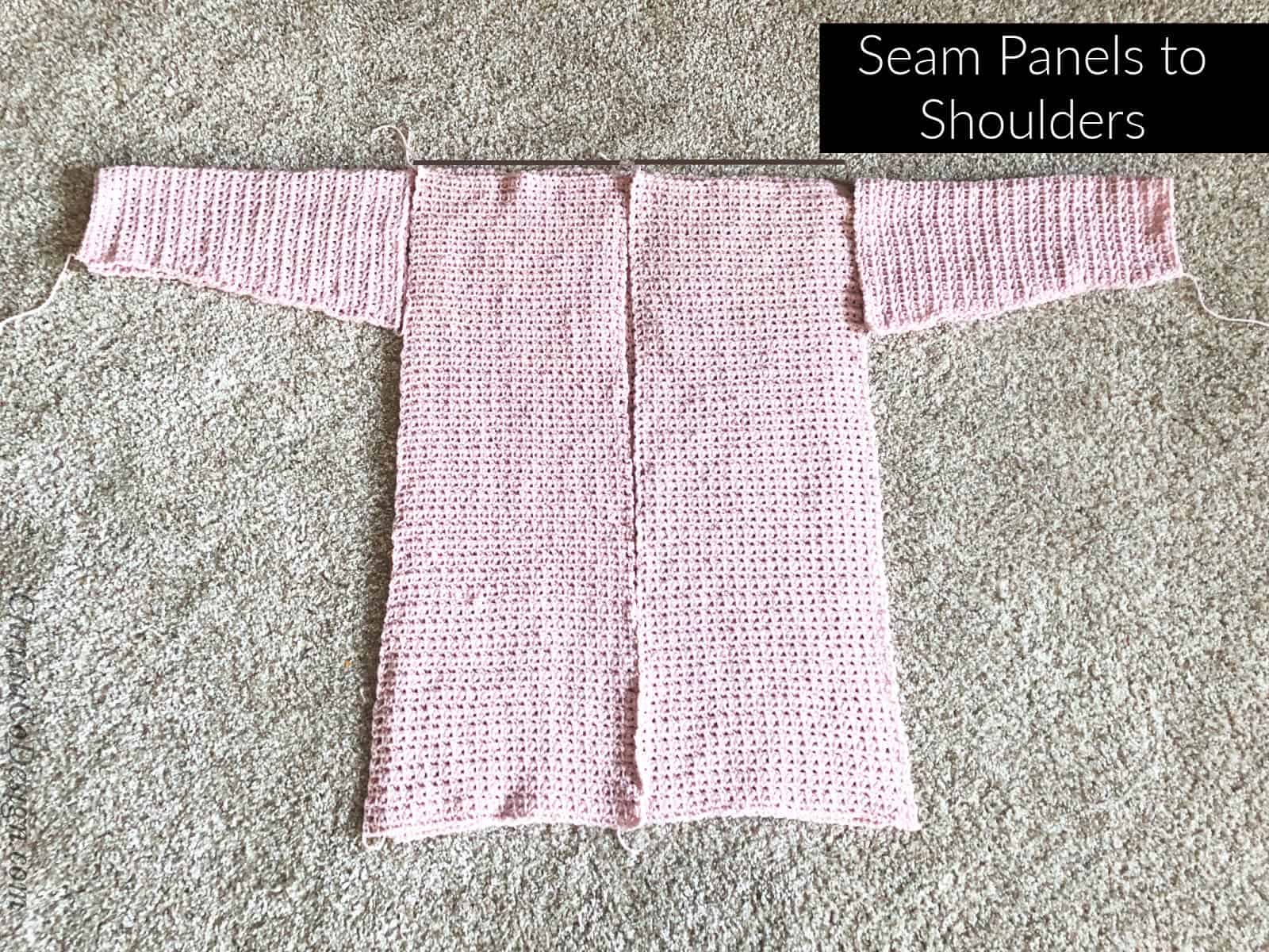 Pink crochet sweater pieces, front panels on back panel, sleeves at side.