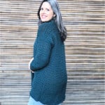 Woman turned to the side wrapped in long crochet cardigan.