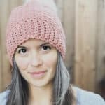 Woman in pink crochet hat with white pom.