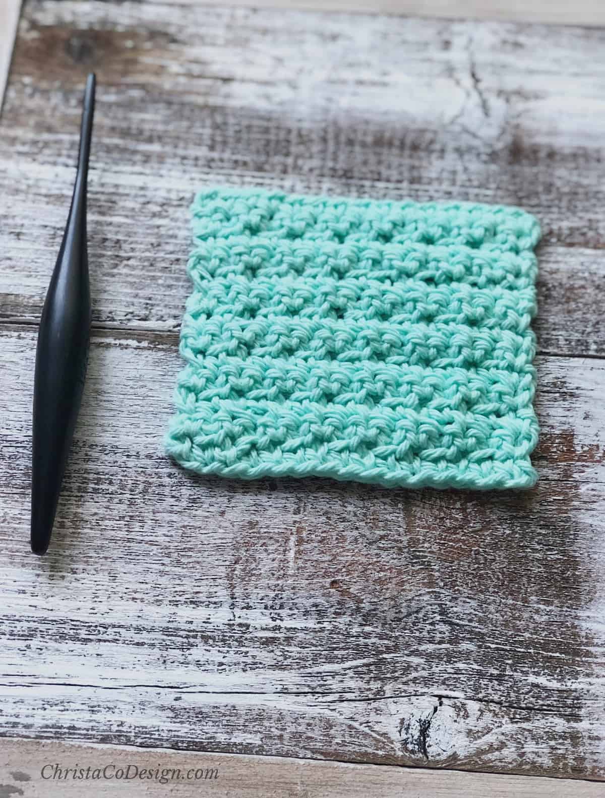 picture of dark wooden crochet hook and mint green square crochet face scrubby