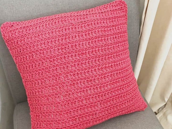 picture of red crochet pillow with envelope closure on grey chair
