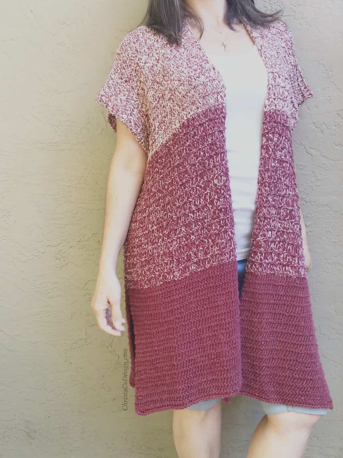 Woman in maroon ombre long knit cardigan over white top.
