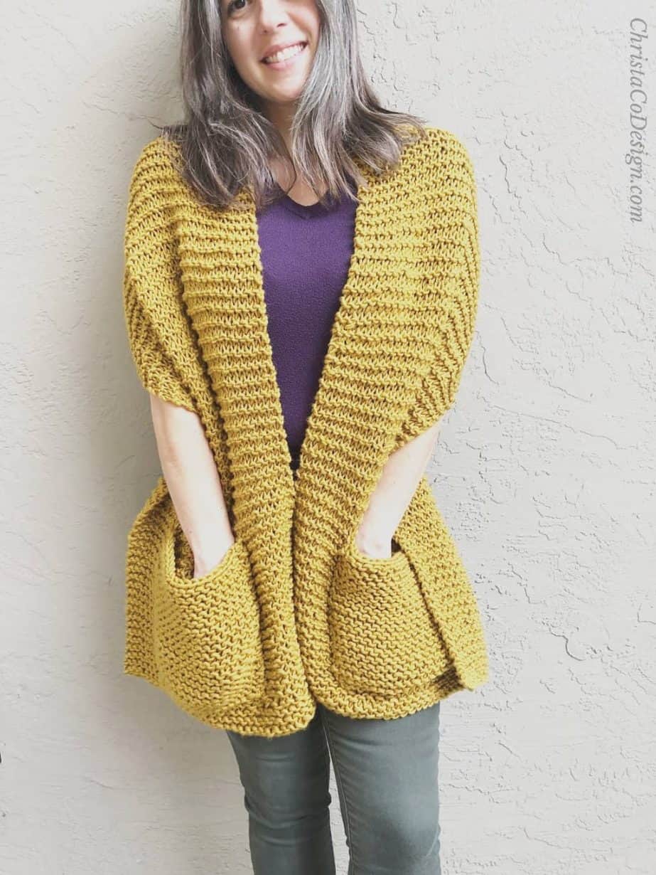 Woman wrapped in honey colored knit pocket shawl pattern.