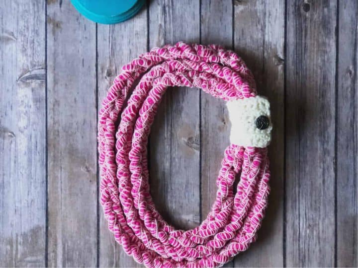 picture of a pink crochet chunky necklace laid flat button cuff in white