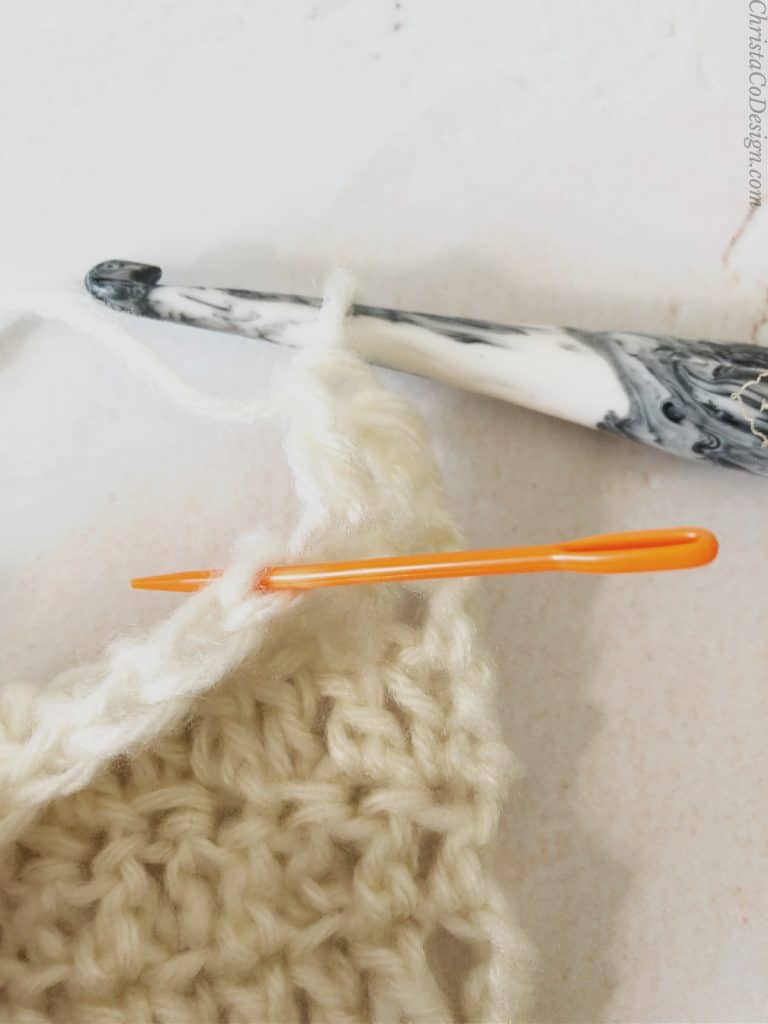 Orange yarn needle in blo of dc stitch.