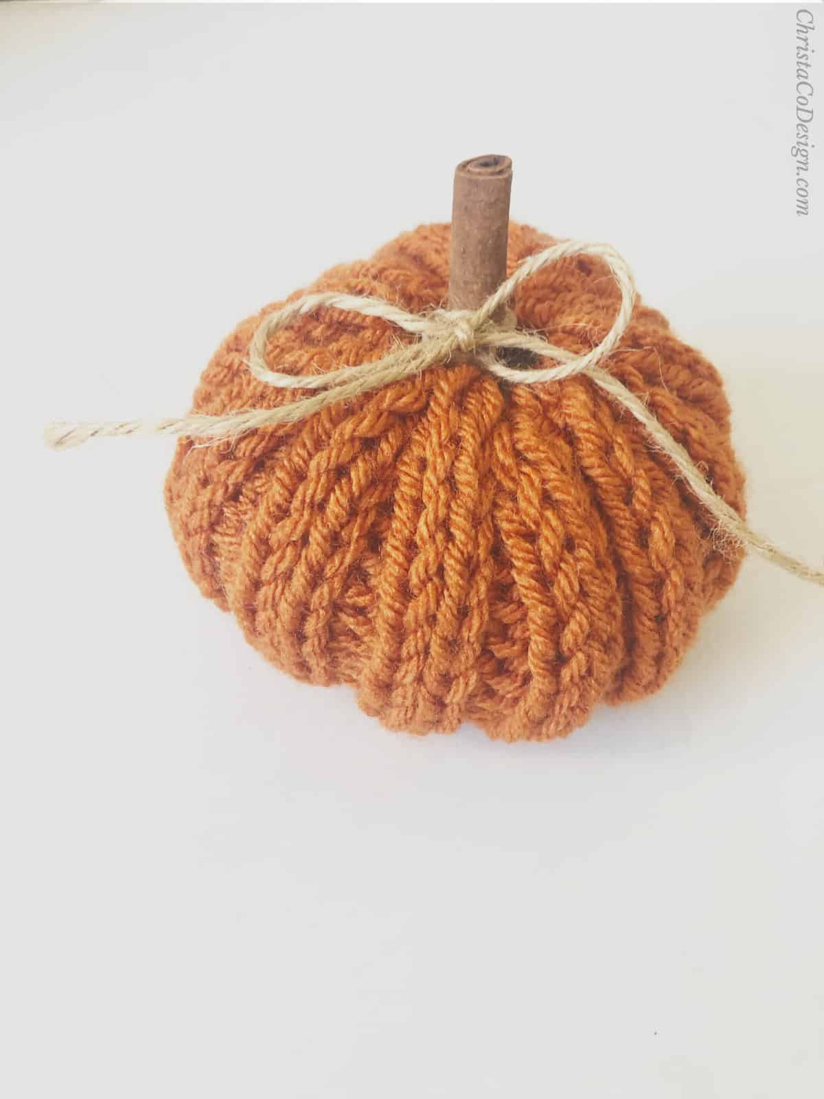 Knit pumpkin in rustic orange with cinnamons stitch for stem and twine bow.