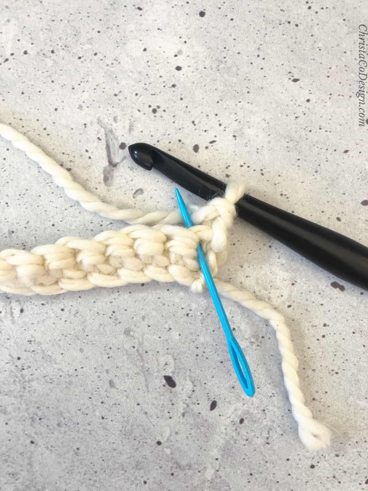picture of blue yarn needle in first stitch of second row