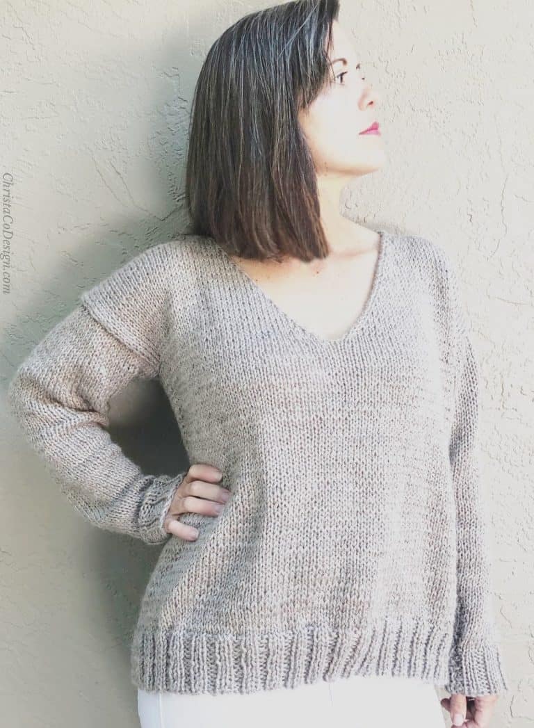 Woman turned in beige v-neck knit sweater.