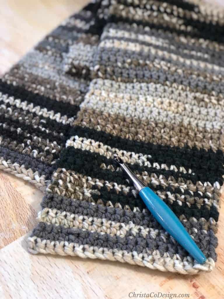 Black and grey beginner crochet scarf with turquoise hook.