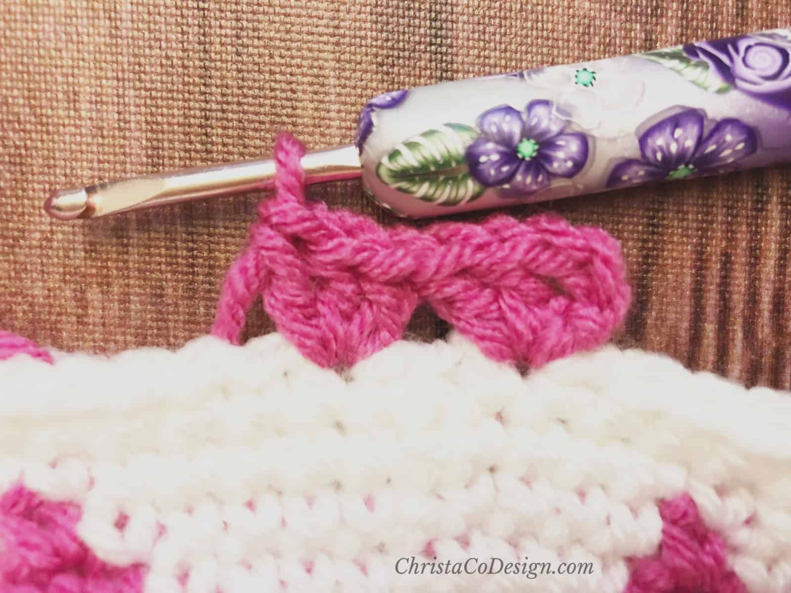 Pink shell stitch border on white crochet hat.