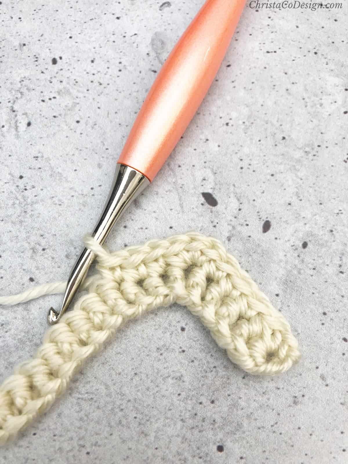 3 single crochets down from peak.