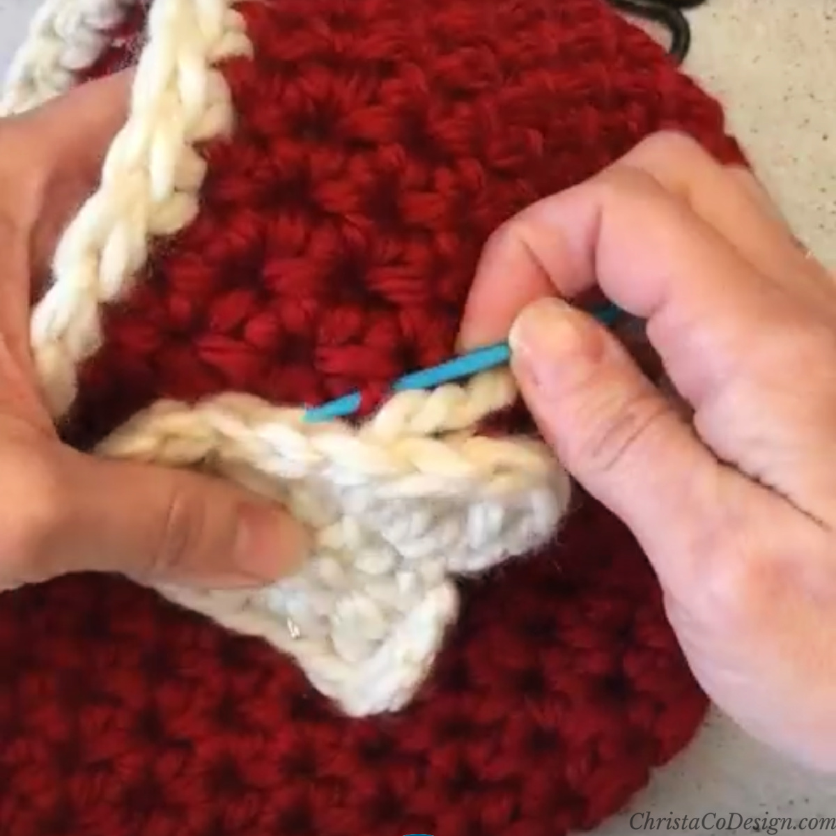 Pick up one loop of hat to thread yarn needle through.