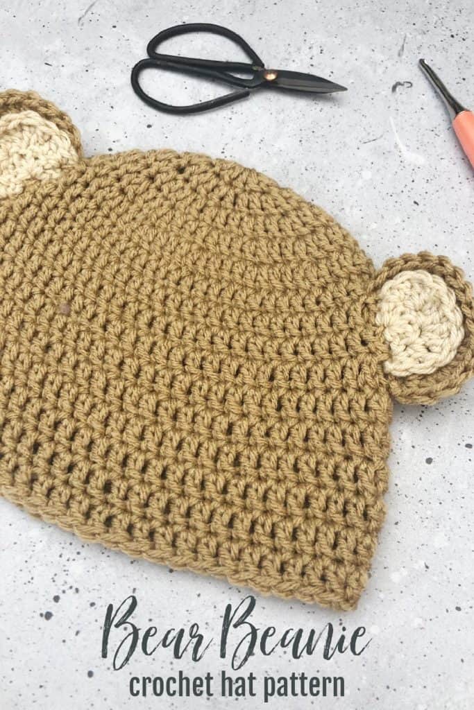 Crochet bear ear hat with scissors and hooks.