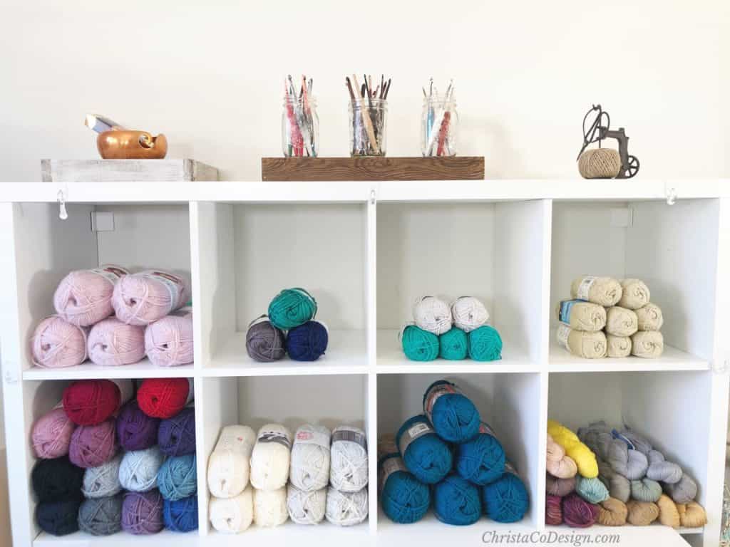 Shelf with yarn and hooks on top in jars.