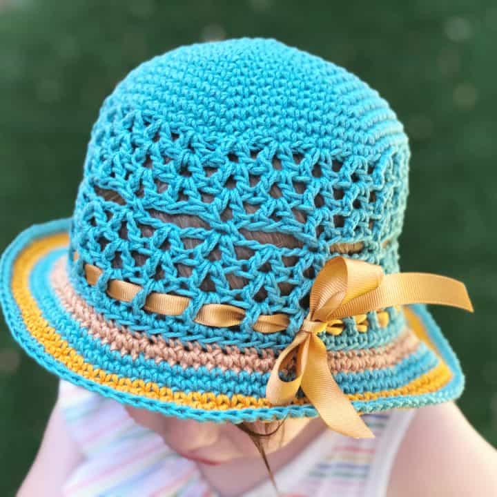 Toddler in teal crochet sun hat with brim.