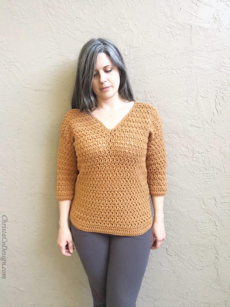 Woman in v-neck crochet sweater camel color.