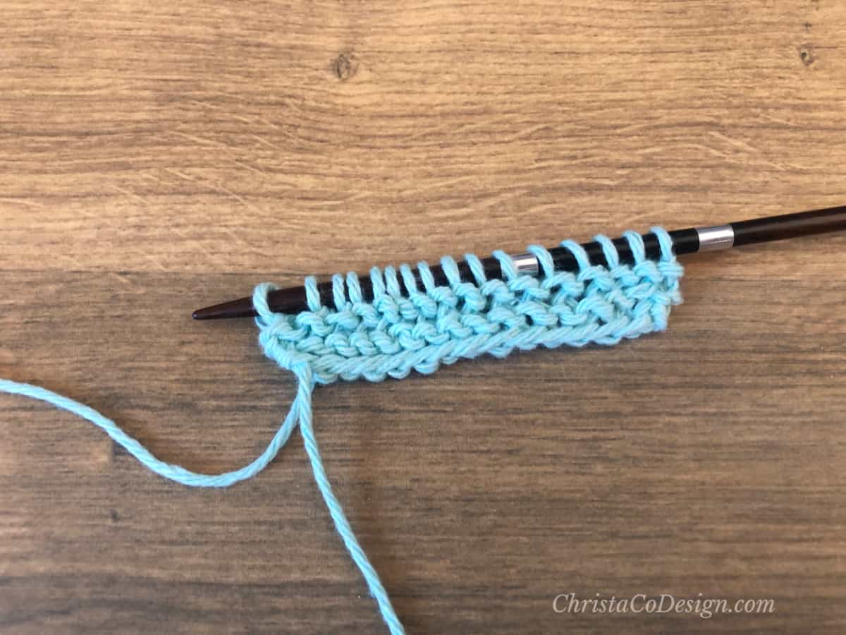 Garter stitch rows in blue cotton yarn on straight needles.