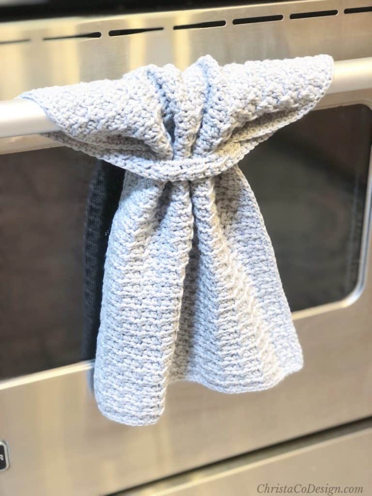 Grey crochet kitchen hand towel hanging from oven handle.
