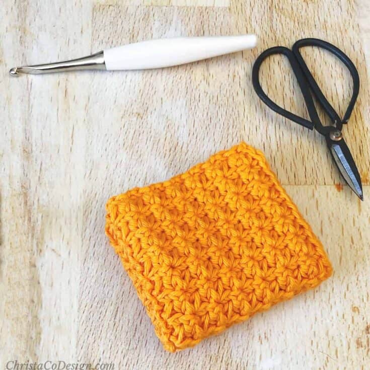 Orange textured Dishcloth pattern folded up on table.