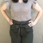 Woman in slim beige crochet top with ruffle sleeves.
