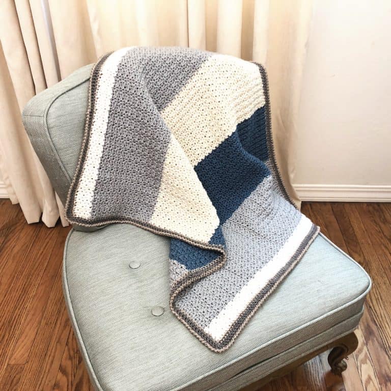 Grey, cream and blue striped crochet baby blanket pattern on chair.