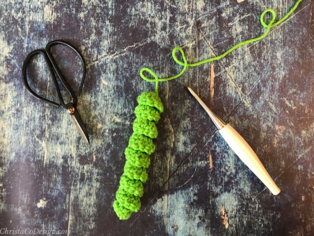 Scissors, green crochet curly Q, white crochet hook.
