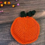 Pumpkin coaster on table.