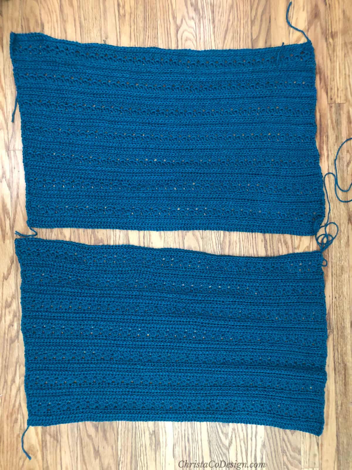 Two blue textured crochet rectangles laid on wood floor ready to be seamed into poncho.