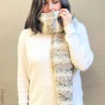 Woman with knit scarf wrapped around neck and mouth.