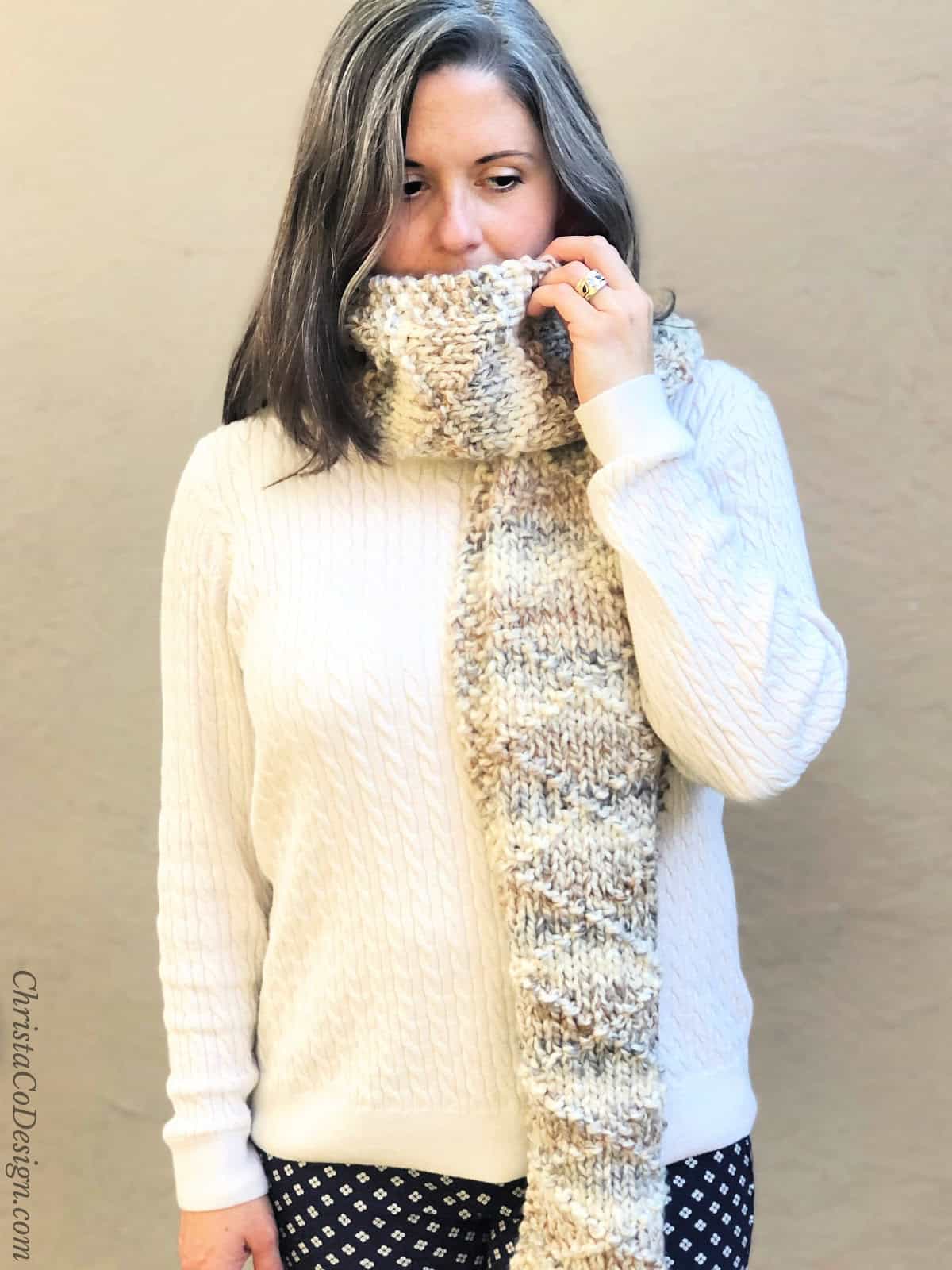 Woman with knit scarf wrapped around neck and mouth.
