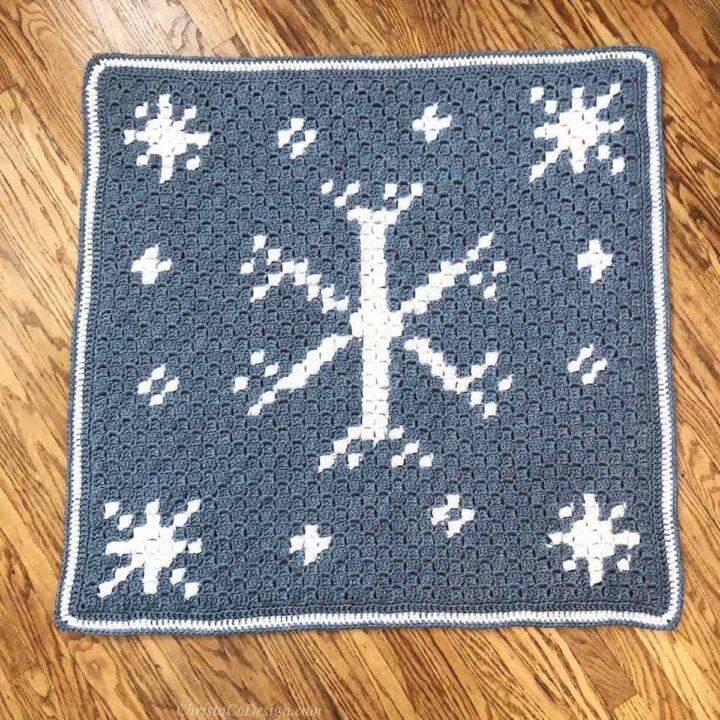 Blue and white crochet blanket with large center snowflake and small ones around it.