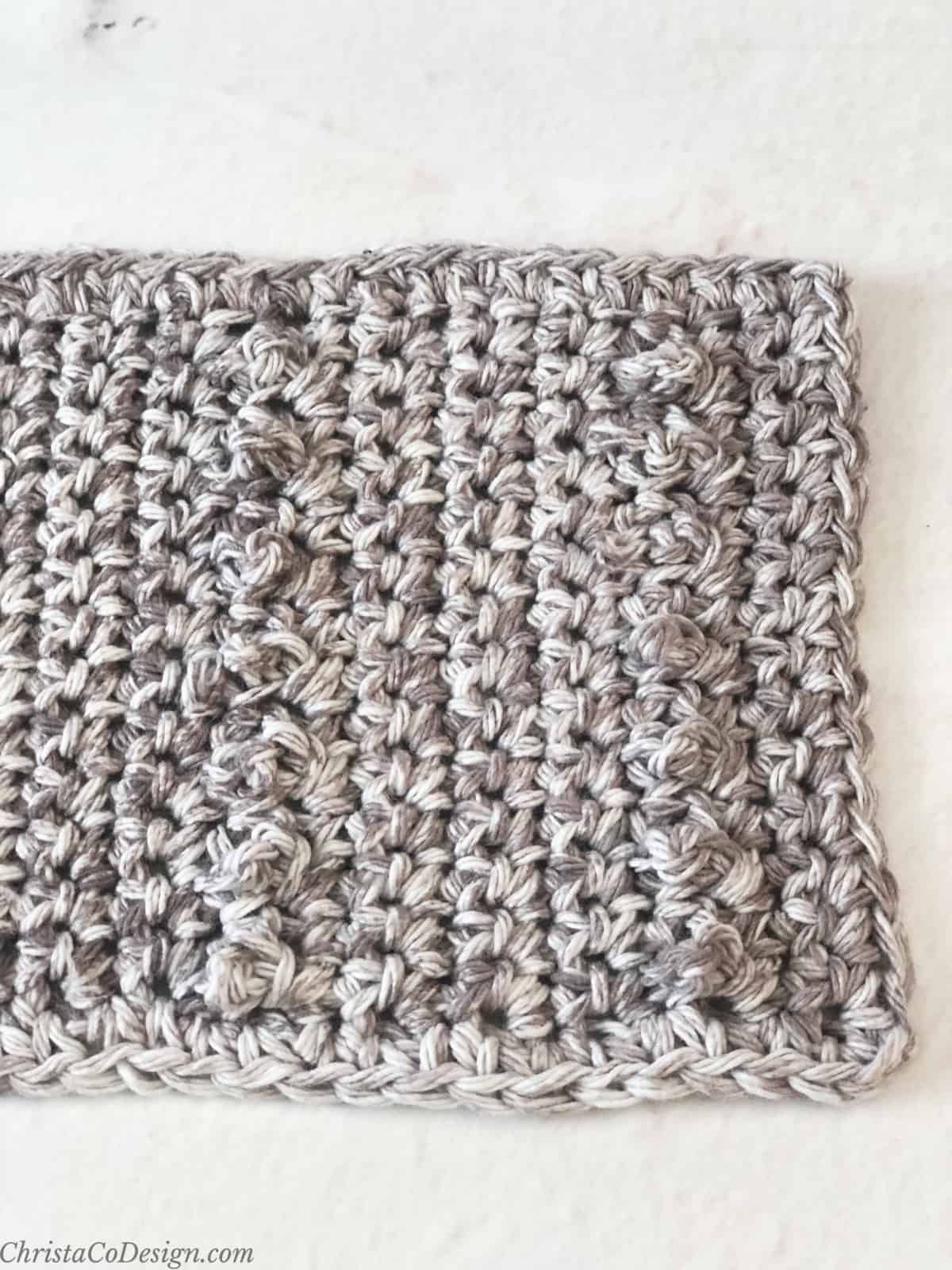 Close up of crochet mug rug with spoon area in grey mottled yarn.
