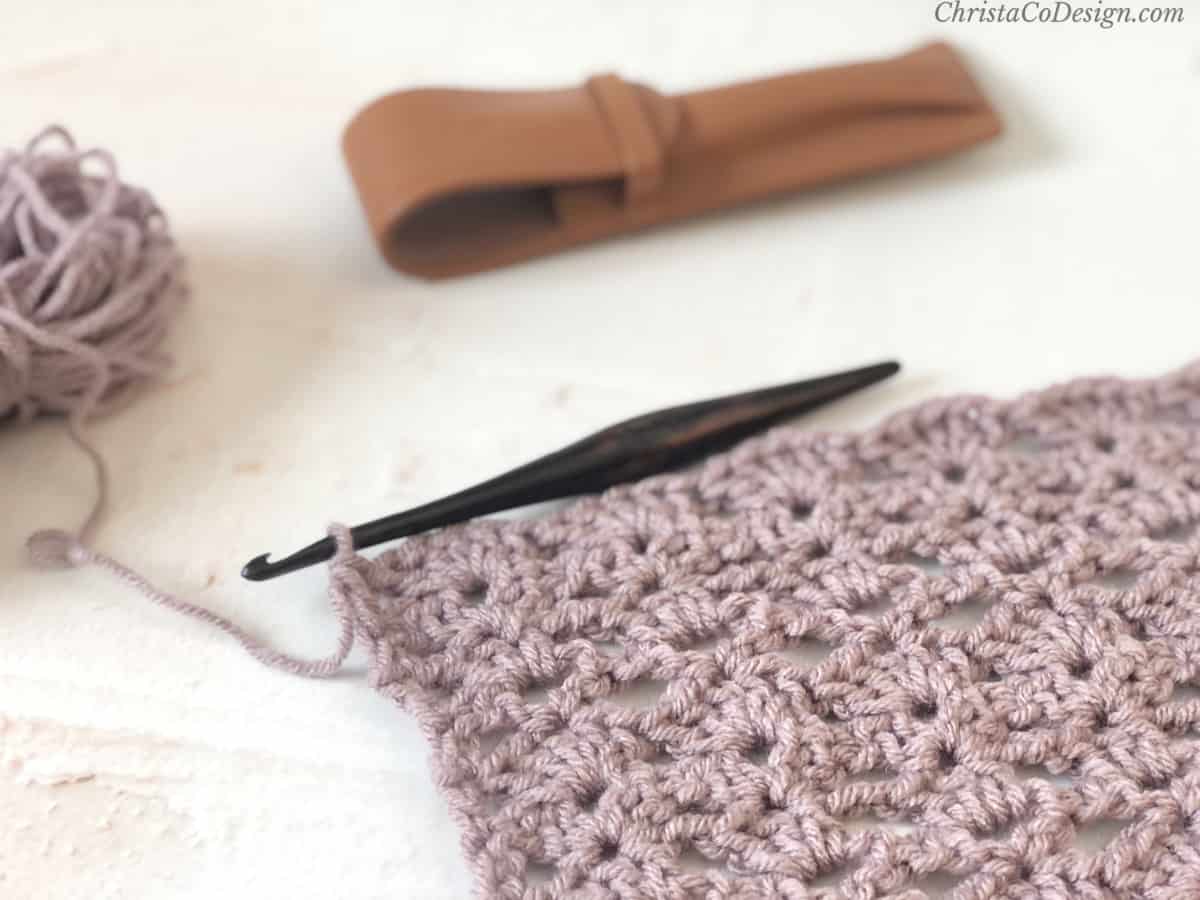 Progress of crochet shawl in purple yarn with streamline hook.