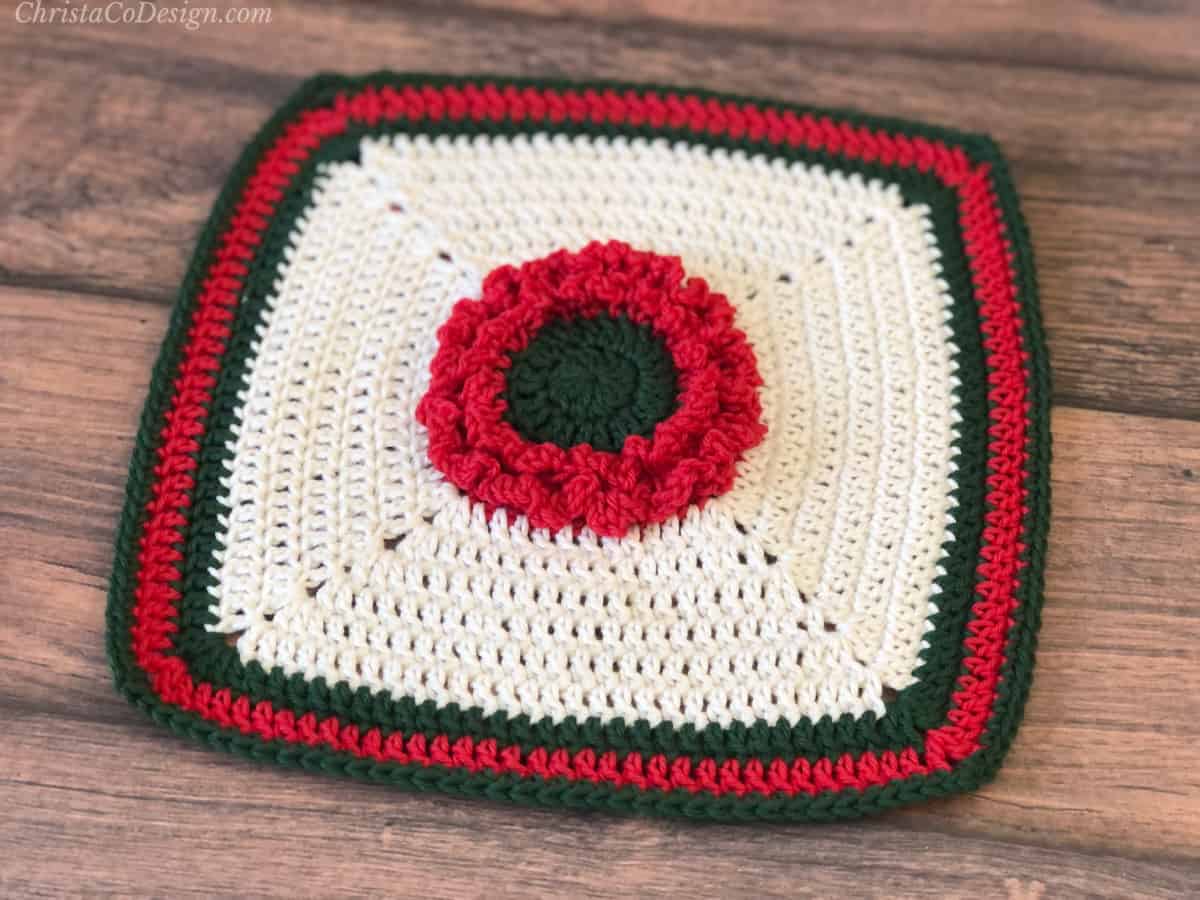 Crochet blanket square with flower at center in red.