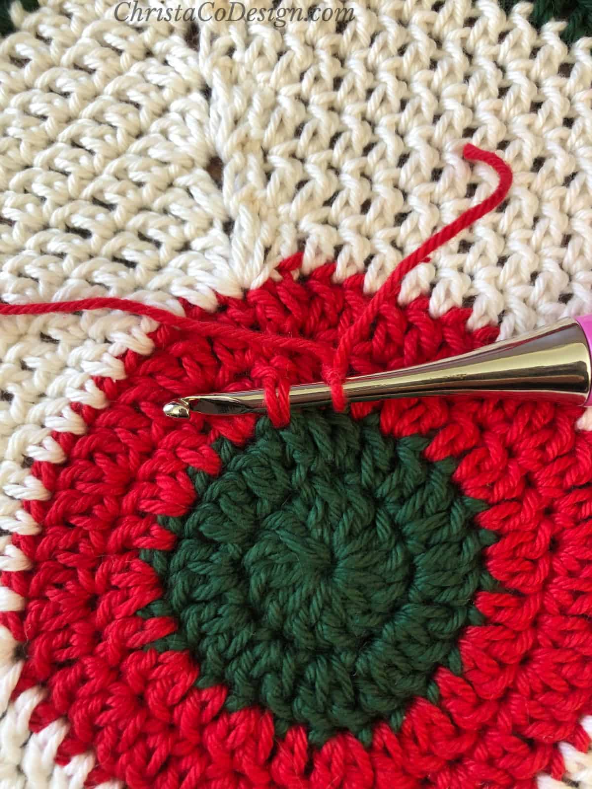 Crochet hook inserted on surface of granny square.