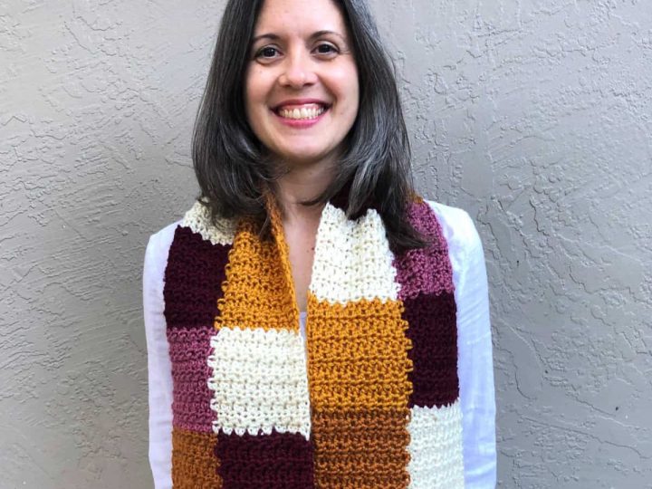 Woman smiling while wearing color block scarf in autumn colors.