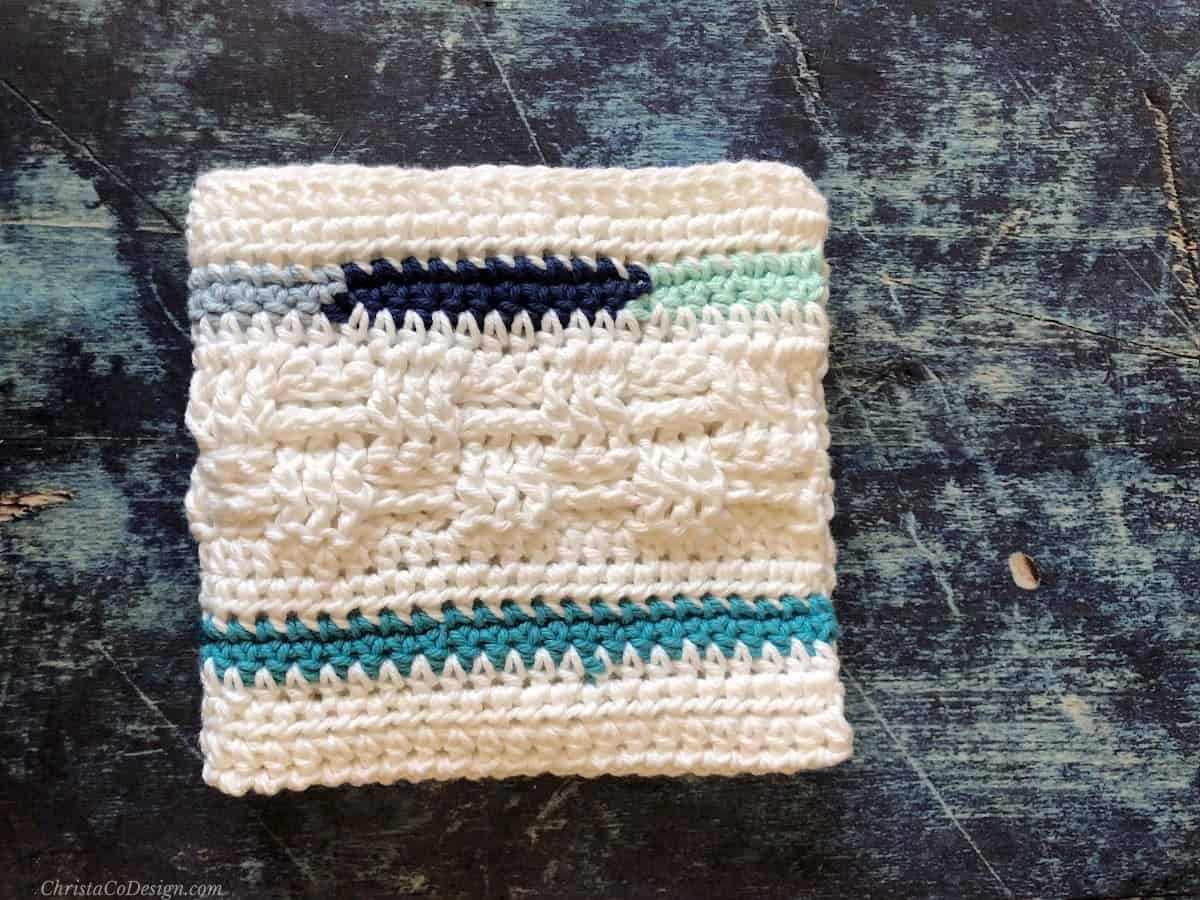Crochet basketweave washcloth in white and blue folded in square.