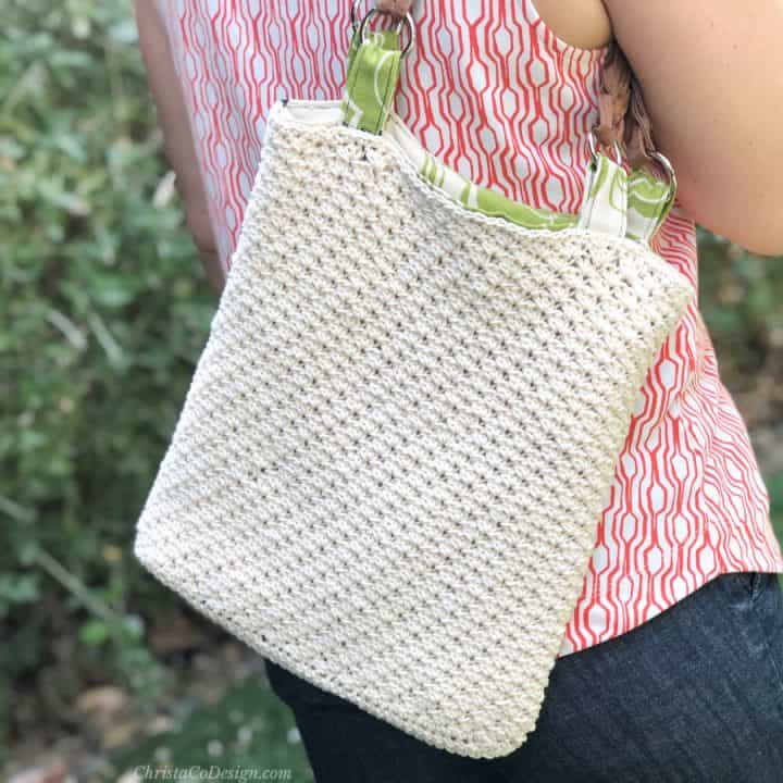 Woman with crochet bag and green liner on shoulder.
