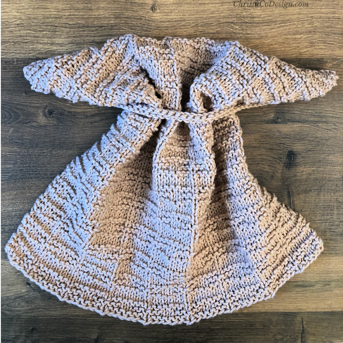 Beige knit dish towel with hanging loop threaded.