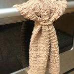 Beige textured knit towel hanging from stainless steel oven bar.