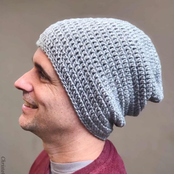 Man smiling in grey slouch beanie turned to side.