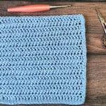 Blue crochet dishcloth with hook and scissors.