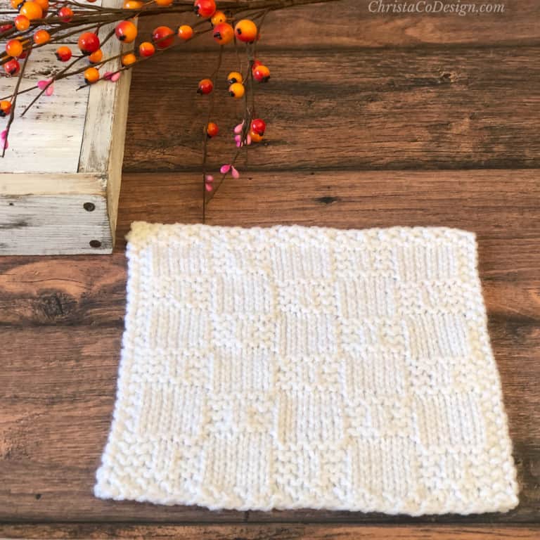 White knit square with textured check pattern on wood table.