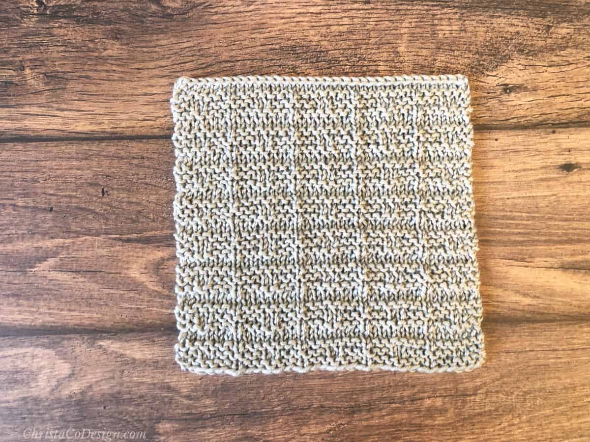 Grey knit blanket square on wood table.