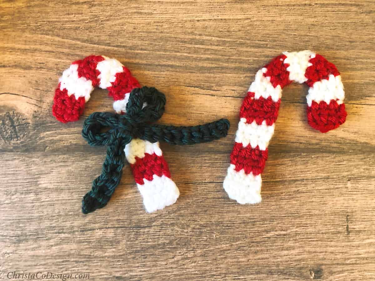 Two crochet candy canes facing out from each other, one with green bow.