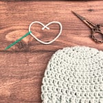 Crochet hat with ribbing next to yarn heart on table.