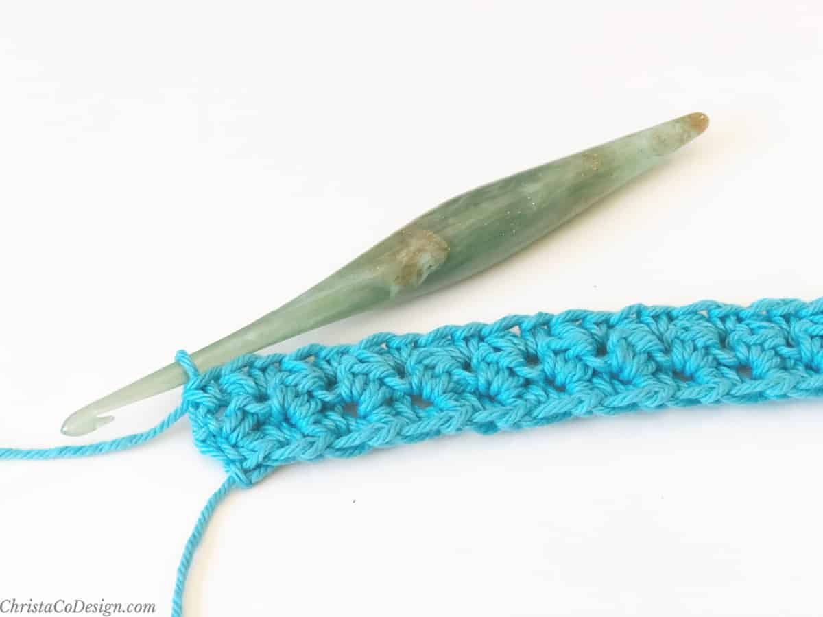 Green crochet hook and first few rows in blue yarn .